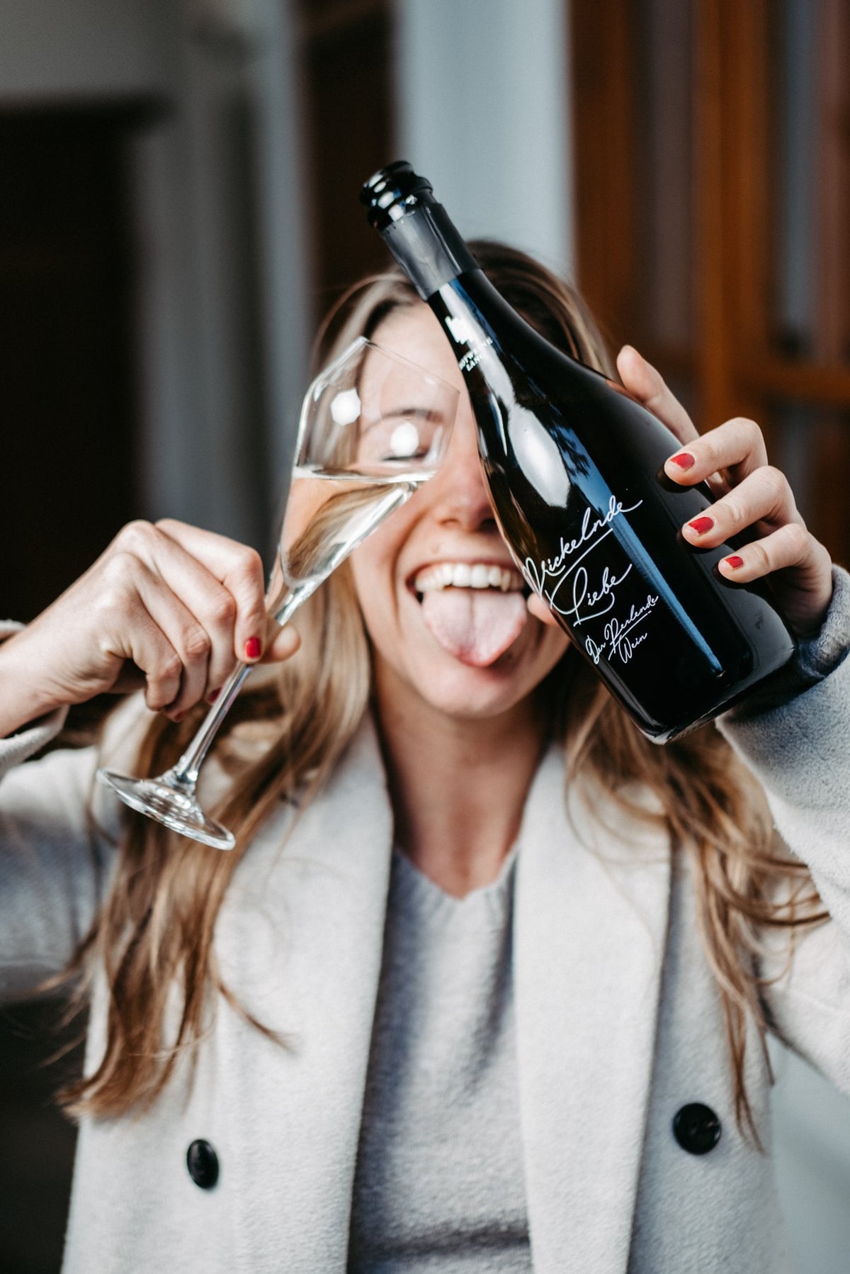 Anna Lang, lachend mit einer Flasche und einem Sektglas